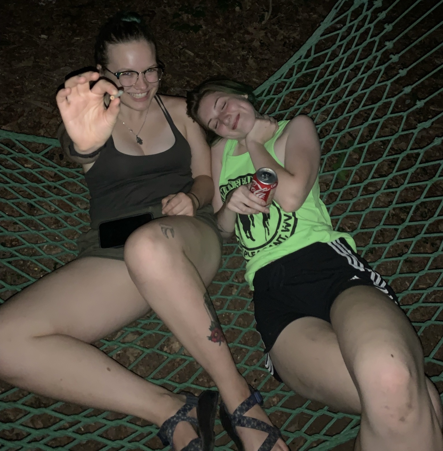 JQ and Ashley sitting on a green hammock. JQ is offering you something.