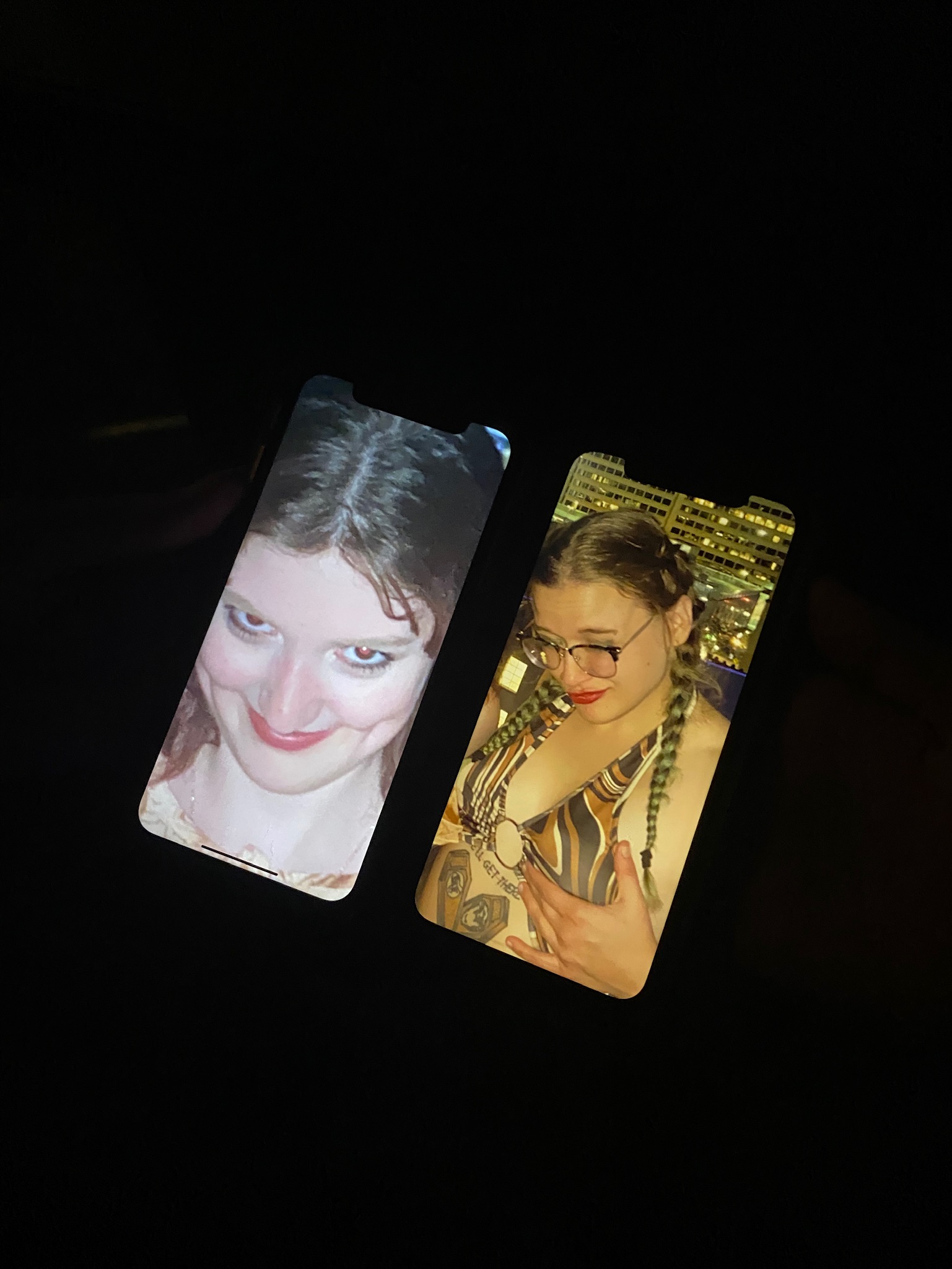 Ashley and JQ as screensavers on two iphones next to eachother in the dark.